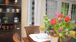 Une table à manger avec une assiette blanche, un vase de fleurs et une chaise en bois.