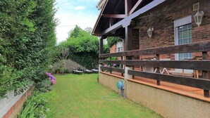 Un jardin avec une clôture en bois, un mur en briques et un enrouleur de tuyau d’arrosage.