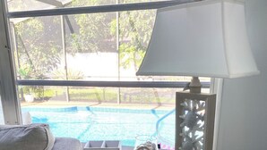 Habitación con vista a una piscina, una lámpara, un estante con toallas dobladas y un cartel que indica prohibido fumar.