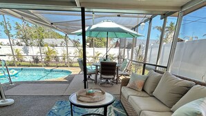 Un patio exterior con piscina, un área de estar cubierta y vistas del paisaje circundante.