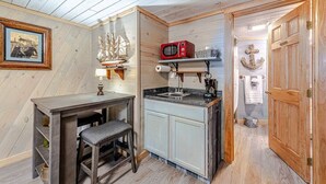 A compact kitchen with a wooden table, a bench, a microwave, and a ship model on the wall. - Captain's Quarters at Island Breeze of CB (Carolina Beach)