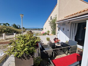 Eine Terrasse mit Gartenmöbeln, Kübelpflanzen und Meerblick.