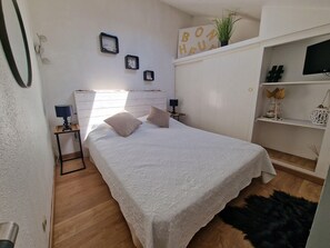 Ein Schlafzimmer mit einem Bett, Nachttischen, einer Ablage mit Dekoration und einem Fernseher.