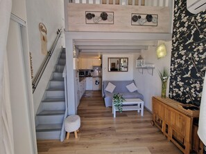 A modern interior with a staircase, a living area with a sofa and coffee table, a kitchen, and a decorative wall.