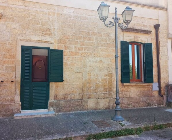 Un edificio de piedra con dos ventanas, cada una con contraventanas verdes.