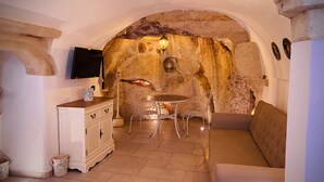 A cozy interior with a stone wall, a fireplace, a sofa, and a dining table.
