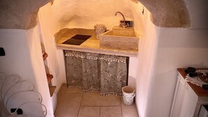 A kitchen with a stone sink, a small window, and a decorative metal gate.