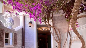 A cozy outdoor seating area with a table and chairs, a small garden with artificial grass, and a tree with purple flowers.