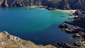 A coastal landscape with a clear blue sea, rocky cliffs, and a sandy beach. - Insolite Tonneau Avec Bulle, en Forêt (Pouldergat)
