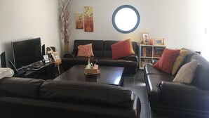 Una sala de estar con televisor, sofás, una mesa de centro y una estantería.