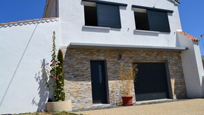 Una casa moderna de dos pisos con fachada de piedra, un garaje y plantas en macetas.