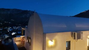 A building with a white dome roof, a small outdoor seating area, and an air conditioning unit. - Bluegonia. (Έξω Γωνιά)