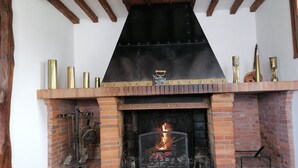A brick fireplace with a black metal hood and decorative brass items on top. - Maison LA Longe'yeres (Saint-Martin-le-Gaillard)