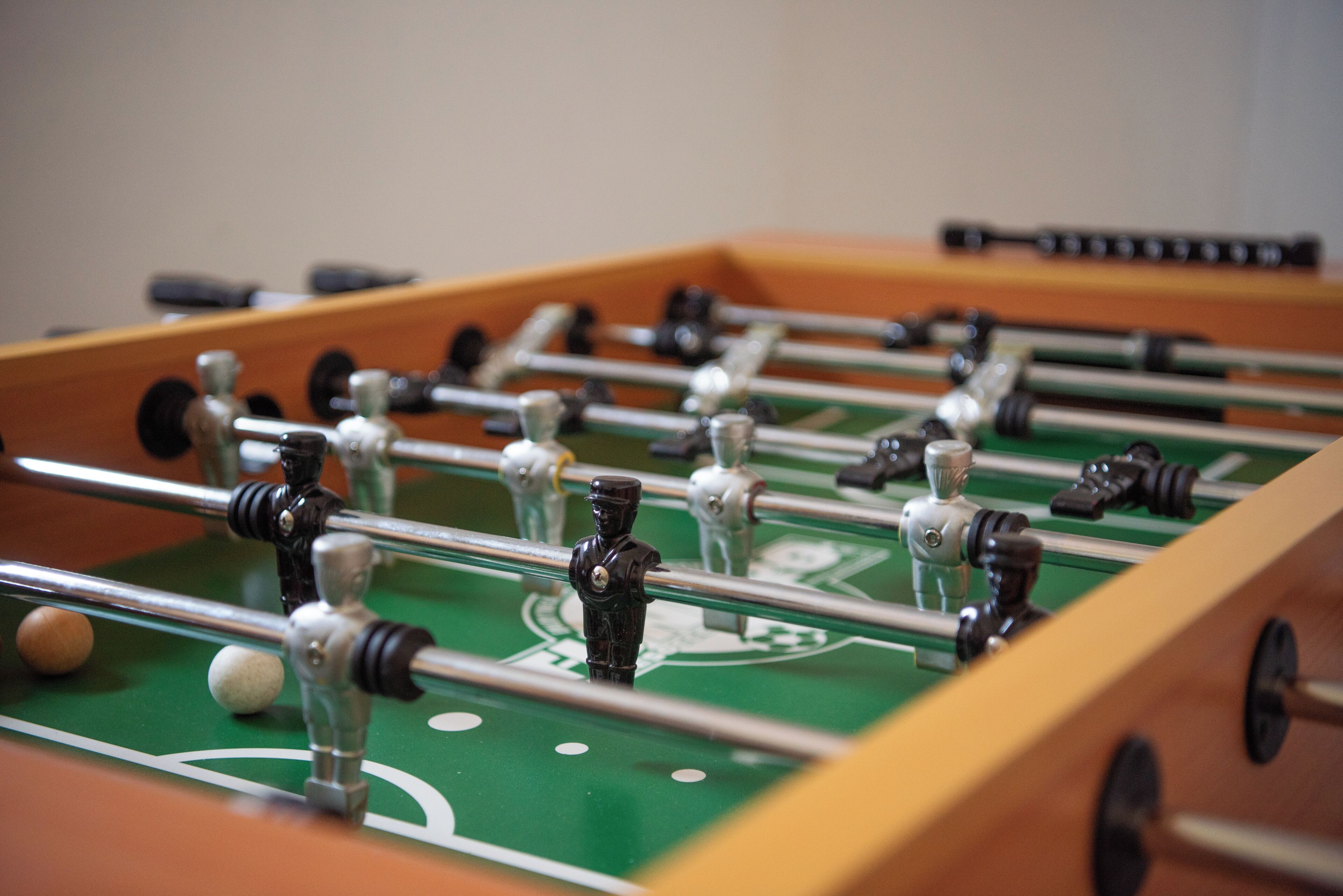 Gros plan d’un baby-foot avec un tapis de jeu vert et des barres métalliques.