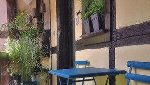 A patio with a blue table and chairs, potted plants, and a wooden fence.
