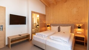 Een moderne hotelkamer met een groot bed, een aan de muur bevestigde televisie, en houten lambrisering.