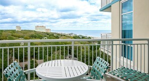Enjoy a meal or a moment of peace on this balcony overlooking the coastal area with views of buildings and lush greenery.