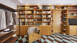 Una habitación con una amplia estantería llena de libros, un escritorio de madera, una silla y un piso con diseño.