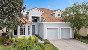 A two-story house with a white exterior, a brown tiled roof, and a garage.
