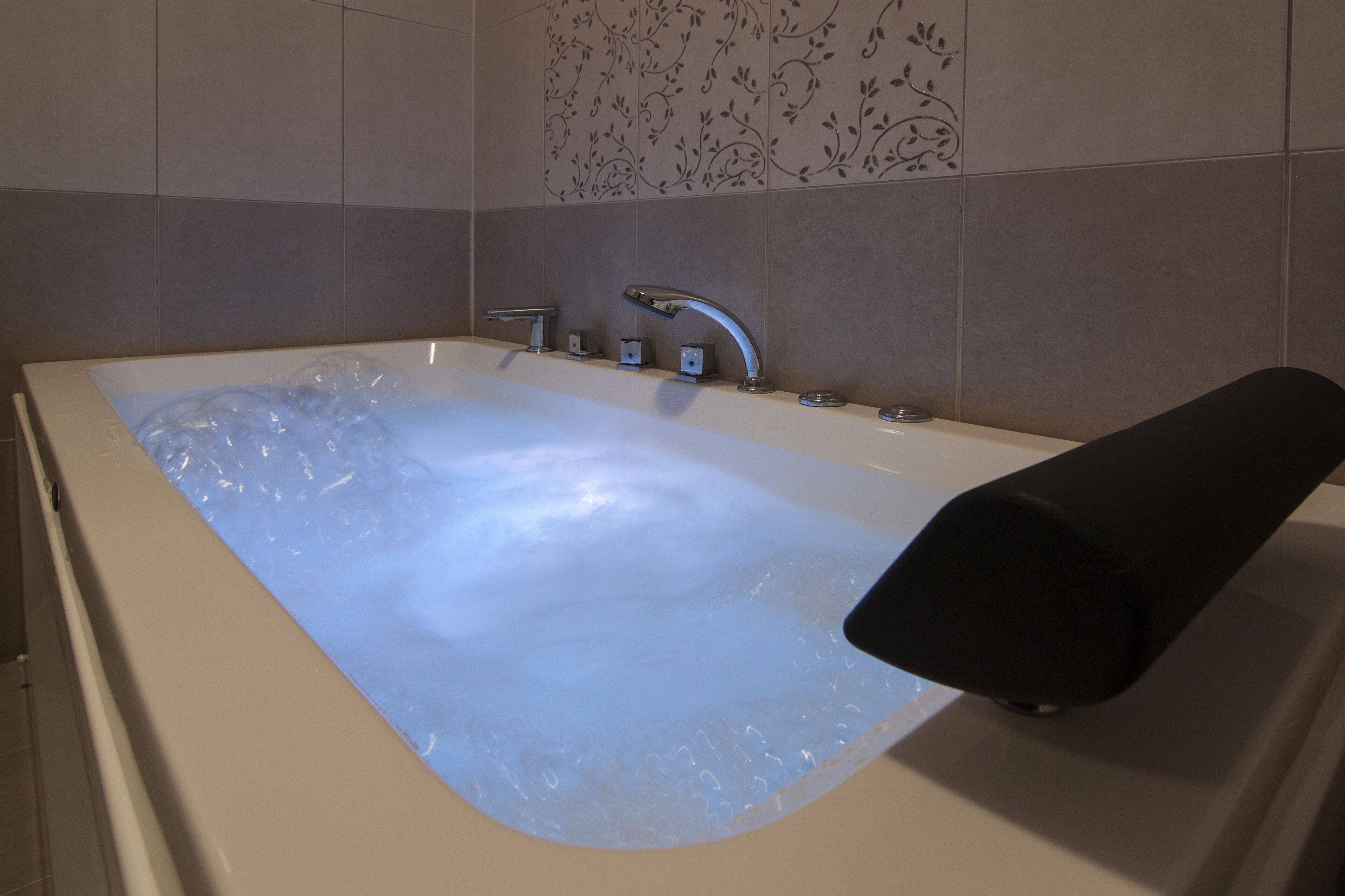 Une salle de bain moderne dotée d’une grande baignoire, d’une douchette à main et d’un siège intégré.