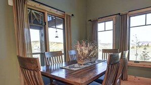 Comedor con mesa de madera, seis sillas y un jarrón de plantas secas.