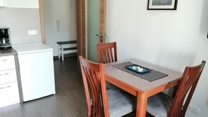 A dining area with a wooden table and chairs, a small black tray with food, and a white refrigerator in the background. - Wohnung für 2 in Einer Villa mit Wunderschönem Meerblick (Karlobag)