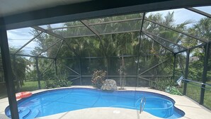 Une piscine couverte offrant une vue dégagée sur les palmiers et agrémentée d’un élément décoratif rocheux en arrière-plan.