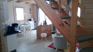 A spacious living area with a wooden staircase, a kitchen, and a dining area. - Blockbohlenhaus "steiner Lodge" (Steinen)