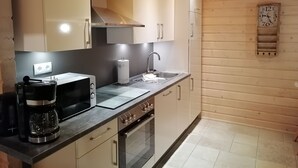 A modern kitchen with wooden cabinets, a microwave, a coffee maker, and a sink. - Blockbohlenhaus "steiner Lodge" (Steinen)