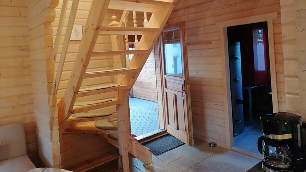 A wooden staircase leading to a second floor, a coffee maker on a table, and a door to the outside. - Blockbohlenhaus "steiner Lodge" (Steinen)