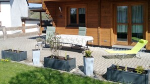 A wooden house with a balcony, a table with chairs, and potted plants. - Blockbohlenhaus "steiner Lodge" (Steinen)