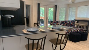 A modern kitchen with a central island, bar stools, and a colorful patterned bench. - Welcome to Our Little Slice of Heaven on the Lake! (Lake Lure)