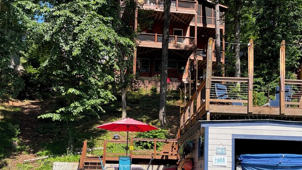 A dock with a boat house, outdoor seating, and a red umbrella. - Welcome to Our Little Slice of Heaven on the Lake! (Lake Lure)