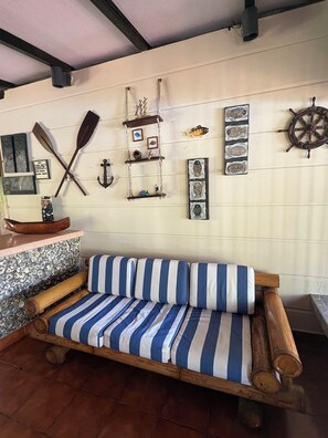 A room with a wooden bench, a striped sofa, and various nautical-themed decorations on the wall.