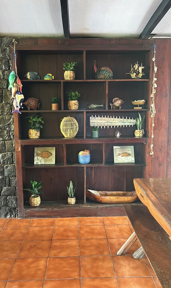 A wooden shelf with various decorative items including woven baskets, framed artwork, and small potted plants. - Rancho frente a la playa (Cuco)