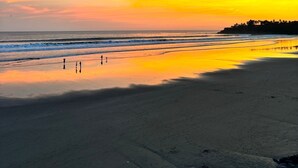 Une plage au coucher du soleil, avec des vagues calmes et un ciel dégagé.