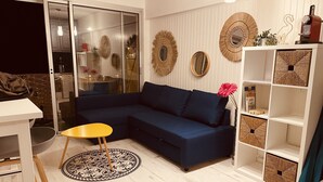 Ein modernes Wohnzimmer mit einem dunkelblauen Sofa, einem gelben Beistelltisch und einem gemusterten Teppich.