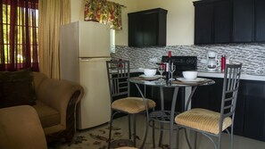 A compact kitchen with a refrigerator, a dining table with chairs, and a coffee maker.