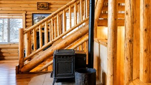 Ein Holzinnenraum mit einer Treppe, einem schwarzen Herd und einem Mülleimer.