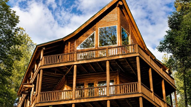 Eine Holzhütte mit Balkon, großen Fenstern und einem Steinfundament.