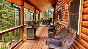 Eine Holzterrasse mit Grill, Stühlen und einem Tisch.
