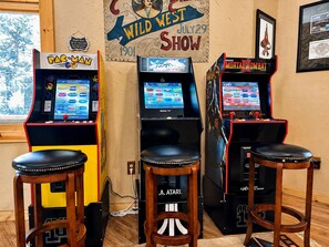 Máquinas de arcade, taburetes de madera y un cartel del Espectáculo del Lejano Oeste.