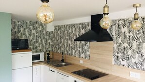 A modern kitchen with white cabinets, a black range hood, and a patterned backsplash.