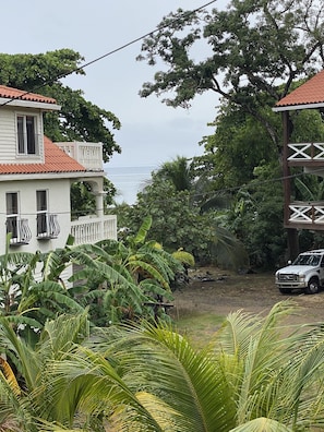 Overlooking a serene body of water, this two-story house offers a tranquil retreat surrounded by lush greenery and a balcony.