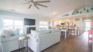 A spacious living area with a large sofa, a ceiling fan, and a dining area with a table and chairs. - Stunning Harbor Views! Boat Slip, 2 King Bedrooms, (Carolina Beach)
