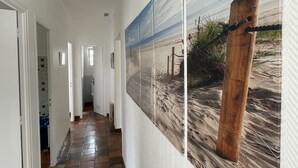A hallway with a tiled floor, white walls, and a series of framed pictures depicting a beach scene. - Pretty house in a large garden / town center,  (La Flotte)