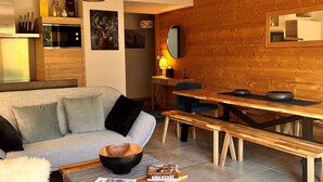 A modern living room with a sofa, coffee table, and wooden dining table.