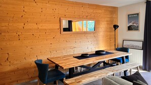 A modern dining area with a wooden wall, a wooden table, blue chairs, and a bench.