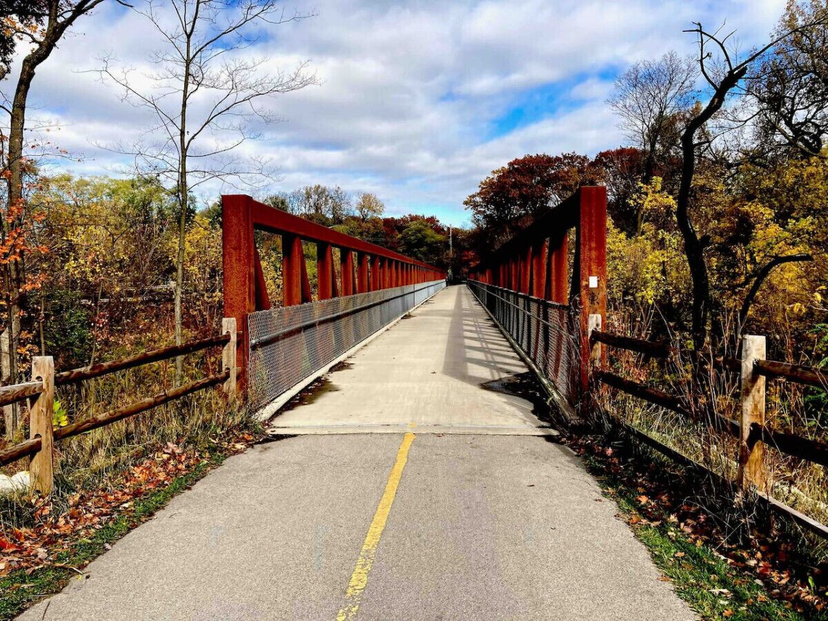 A pedestrian bridge with a metal railing and a concrete path.