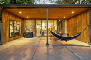 A covered patio with a hammock, a barbecue grill, and a dining area with a table and chairs. - Chicago Riverhouse with private fenced in oasis (Chicago)